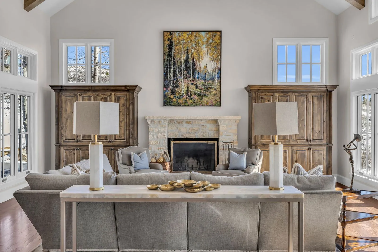 Living room with a stone fireplace, twin armoires and aspen artwork