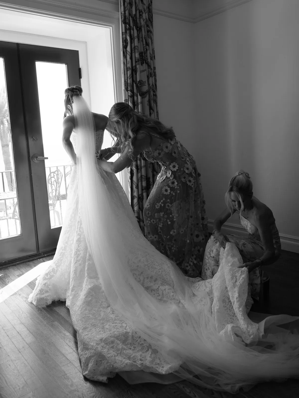 Natalie and her daughters, Halle and Olivia, working together to fasten and arrange a wedding gown